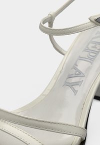 Άσπρο σανδάλι με ψηλό τακούνι, λεπτές λουρίδες και τετράγωνη μύτη, με τη λέξη «Everyday» χαραγμένη στην εσωτερική σόλα.