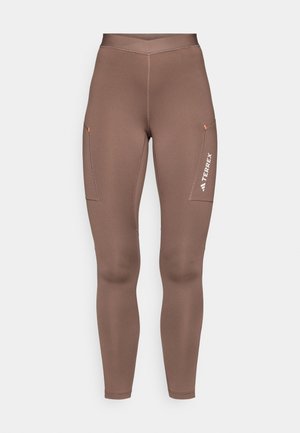 Brown athletic leggings with a smooth texture, high waist, and two side pockets. Notable branding in white on the right leg.