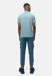 Lyseblå polo skjorte med korte ermer og krage, kombinert med mørkeblå cargo sweatpants med sidelommer og elastiske mansjetter.