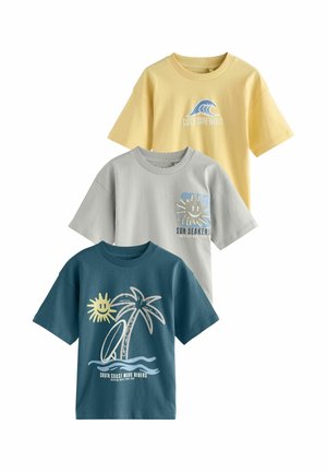 Tre børnet-shirts i gul, lysegrå og blågrøn med strandtema-grafik og sætninger: bølger, sol, palme og surfbræt.