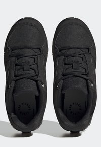 Un paio di scarpe da corsa nere in tessuto testurizzato, con lacci e colli imbottiti, viste dall'alto su uno sfondo chiaro.