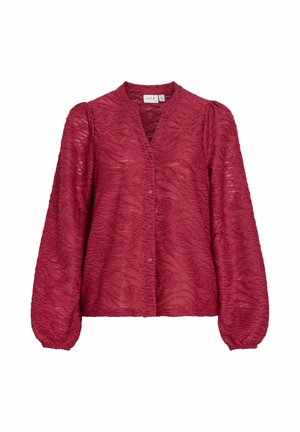 Czerwona teksturowana bluzka z dekoltem w kształcie litery V, zapinana na guziki z przodu i z długimi bufkowymi rękawami. Tkanina ma falisty wzór i subtelny połysk.