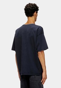 T-shirt en coton bleu marine avec une coupe décontractée, des manches courtes et un col rond. Présente des détails de couture le long des coutures.