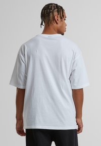 Hvid bomulds T-shirt med en afslappet pasform, korte ærmer og rund halsudskæring. Glat tekstur, ingen synlige mønstre eller grafikker.