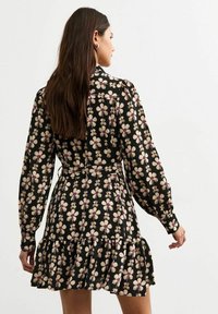 Black floral dress featuring long sleeves, ruffled hem, and a pattern of cream and purple flowers, made from lightweight material.