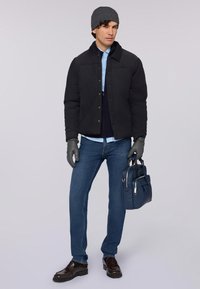 Černá prošívaná bunda s límcem, pod ní světle modrá košile, modré džíny, šedé rukavice a tmavě modrá taška; hnědé boty.