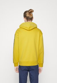 Yellow hooded sweatshirt with a kangaroo pocket, ribbed cuffs, and hem. The back features a simple, clean design without embellishments.