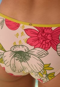 Bikini met bloemenpatroon in lichtroze, met grote roze en groene bloemen. Verfraaid met een limegroene bies.