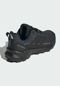Scarpe outdoor Terrex nere con tomaia in tessuto texturizzato, suola in gomma con intagli e un distintivo design a tre strisce.
