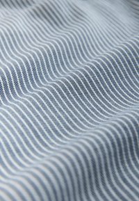 Textília s vlnovým vzorom v svetlomodrých a bielych pruhov, ktorá ukazuje jemné štruktúry a hladkú povrchovú kvalitu.