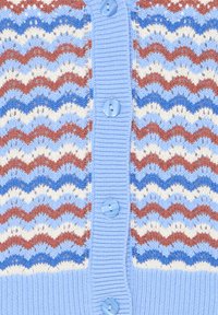 Close-up van een gebreide cardigan met een zigzagpatroon in blauw, roestkleur en crème, met een lichtblauwe knoopsluiting.