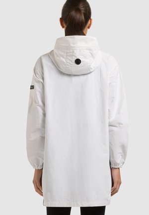 Žena s smeđom kosom u repu, odjevena u dugu bijelu jaknu s kapuljačom i elastičnim manžetnama, prikazana straga na jednobojnoj pozadini.