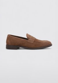 Mocassins en cuir suédé marron avec une semelle plate, un bout rond et une sangle décorative sur le devant. Texture lisse avec de subtils détails de couture.