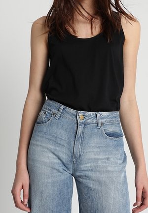 Haut noir sans manches avec un col rond, associé à un jean bleu clair taille haute avec un effet délavé et un design classique à cinq poches.