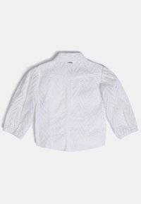 Biała bluzka z długim rękawem z wzorem w zygzaki z koronką, bufiastymi rękawami i małą metką poniżej kołnierza z tyłu.