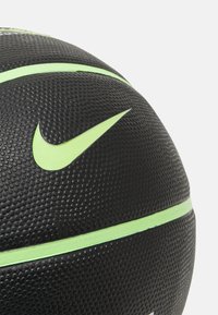 Palla da basket nera con superficie testurizzata, con il famoso swoosh verde della Nike e linee verdi che corrono lungo la sua superficie curvata.