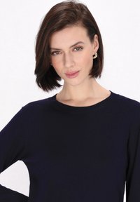 Tengerész kék kötött pulóver kerek nyakkivágással és hosszú ujjakkal. Simma textúra, minimalista dizájn, látható minták vagy kiegészítők nélkül.