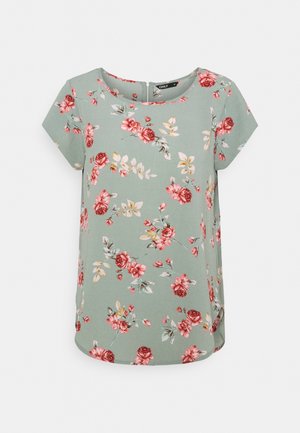 Květovaný top s krátkými rukávy ze zelené látky s motivem červených a růžových růží na světle zeleném pozadí. Kulatý výstřih a boční rozparky.
