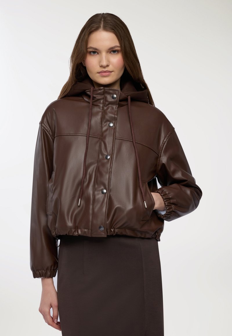 Giubbotto cropped in ecopelle marrone con cappuccio, caratterizzato da bottoni a pressione, polsini elasticizzati e orlo con coulisse. Texture liscia con finitura lucida.