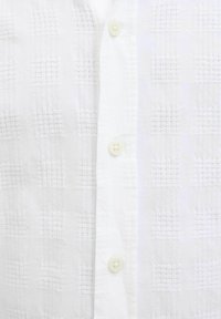 Camicia bianca con bottoni, caratterizzata da un motivo a griglia testurizzato, realizzata in tessuto leggero, con bottoni rotondi bianchi.