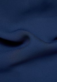 Marineblaue Stoff mit einer glatten, leicht strukturierten Oberfläche, drapiert, um sanfte Falten und subtile Variationen im Glanz zu zeigen.