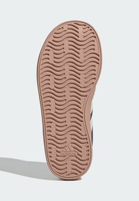 Gumová podrážka boty, s texturou vlnových vzorů, v jemně růžové barvě. Má embosované logo. Hladké okraje, mírně zvýšený podpatek.