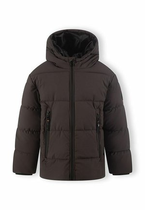 Garçon marchant portant une doudoune noire, un pantalon noir et des baskets blanches, souriant sur un fond gris clair.