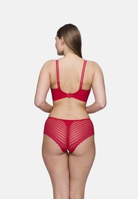 Ensemble de bralette et culotte assortis en dentelle rouge, dotés de bords festonnés, de bretelles réglables et d'un motif en losange au dos.