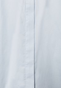 Light blue, woven fabric close-up; features a smooth texture with a prominent vertical seam and crisp, clean lines.