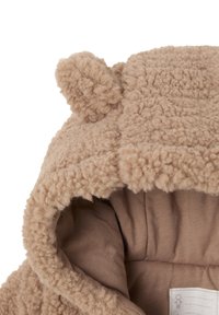 Tan teddy fleece hood with a soft, textured exterior and a cozy inner lining. Features rounded ears on top for added detail.