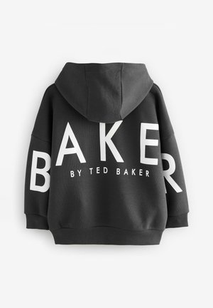Melnā kapuce, izgatavota no teksturēta auduma, ar lieliem baltas krāsas burtiem uz aizmugures, kas lasa "BAKER BY TED BAKER." Izmantojamā ar kapuci un ribotām aprocēm.