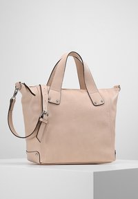 Jasnoróżowa skórzana torebka z podwójnymi rączkami i regulowanym paskiem na ramię. Posiada czarne wykończenia, srebrne okucia oraz usztywniony kształt.