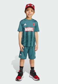 Completo sportivo turchese con logo Marvel, grafica di Spider-Man sulla maglietta, pantaloni corti neri e sneakers con dettagli rossi. Cappellino rosso di Spider-Man e calzini con fantasia.