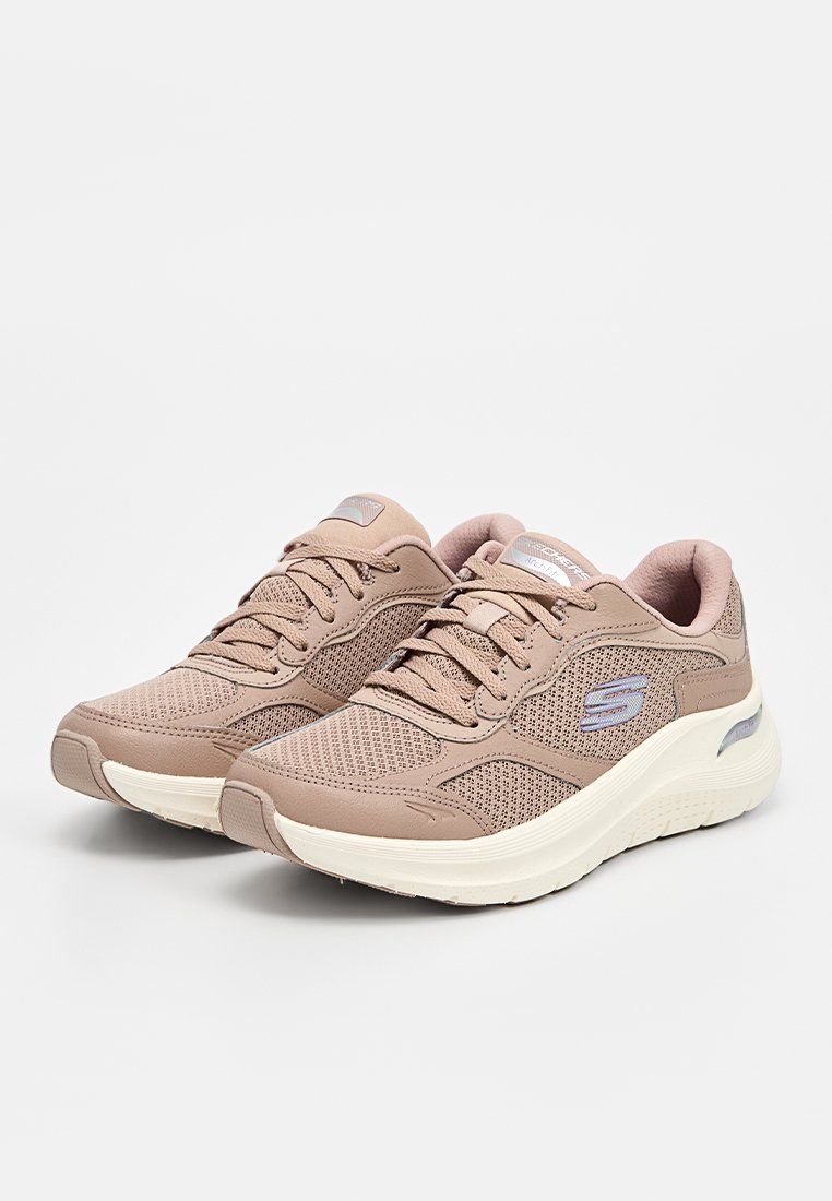 Beige Sportartike Schuhe mit Mesh-Obermaterial, strukturierten Schnürsenkeln und gepolsterter weißer Sohle; verfügt über ein Logo-Element an der Seite und subtile Designdetails.