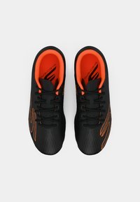 Baskets de sport noires avec une tige texturée, présentant des accents et des lacets orange, ainsi qu'un motif en nid d'abeille sur les côtés.