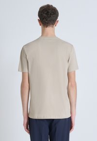 Camiseta beige de manga corta con cuello redondo, que presenta una textura suave y un corte relajado. Sin patrones ni logotipos visibles.