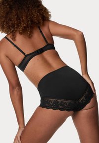 Set di lingerie nera composto da un reggiseno sleek con spalline regolabili e un perizoma a vita alta con bordo in pizzo e motivi floreali lungo l'orlo.