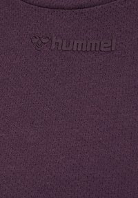 Donkerpaarse gestructureerde stof met het geperste hummel-logo en bijensymbool, gecentreerd vlak bij de bovenrand.