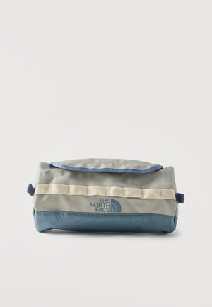 Pochette rectangulaire North Face avec partie supérieure beige, fond bleu, logo sur le devant, fermeture à rabat et passants en sangle beige cousus sur le devant.