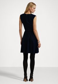 Námornícky zamatový šaty s priliehavým korzetom a rozšírenou sukňou. Obsahuje čapkové rukávy, opasok v páse a zadný zips. Nosené s čiernymi pančuchami a ihlovými podpätkami.