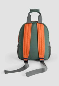 Rucsac din țesătură verde, cu bretele căptușite portocalii, având o formă rotundă și o buzunar lateral din plasă gri. Vedere din spate care arată lungimea și textura bretelelor.