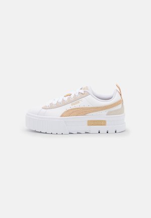 Baskets plateforme Puma blanches et beiges avec semelle épaisse, bande latérale en daim et fermeture à lacets sur fond uni.