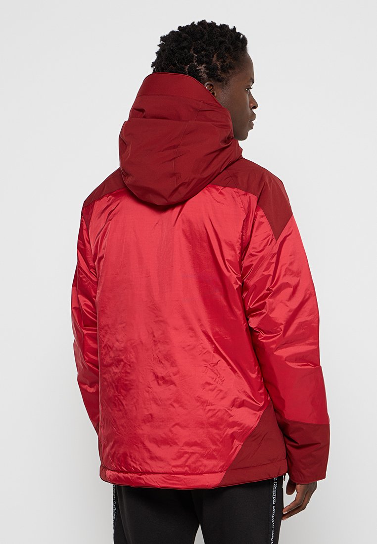 Röd lätt vadderad jacka med huva, med en glänsande yta, kontrasterande vinröda accenter på axlarna och en rak fåll.