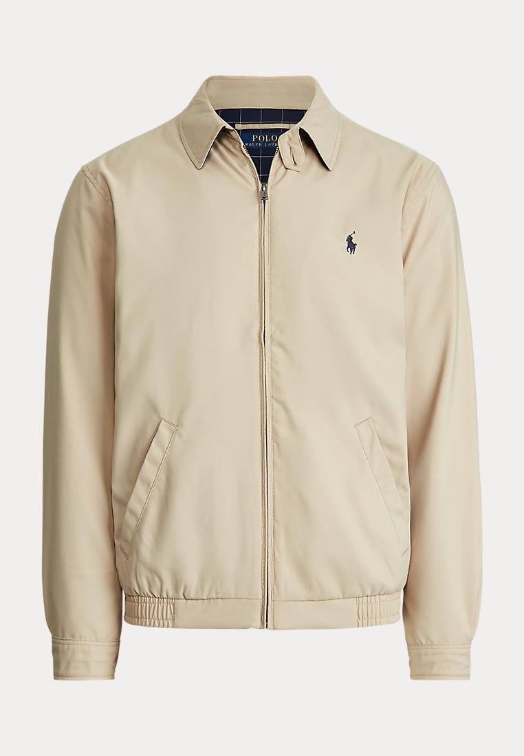 Veste beige zippée avec col, poches latérales, ourlet élastique et petit logo foncé sur la poitrine gauche, présentée sur fond uni.