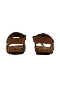 Sandales marron avec des sangles supérieures réglables, semelle en liège et semelle en caoutchouc. Présente un design simple avec un dos ouvert et des matériaux texturés.
