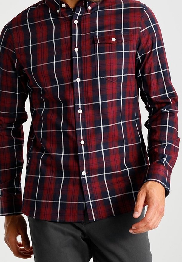 Rood en marineblauw geruit overhemd met een klein borstzakje, witte knopen en lange mouwen, gemaakt van geweven stof met een gladde textuur.