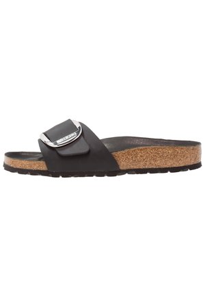 Sort åben sandal med korksål og bred strop med stor sølvspænde på hvid baggrund.