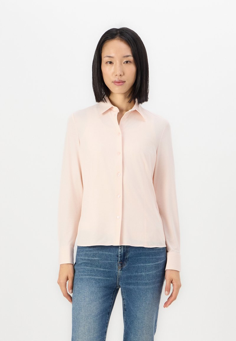 Hele roosa pika varrukaga särk, millel on kaelus ja ees nuppudega kinnitamine. Kangas tundub sile ja veidi läikiv. Sobib siniste teksadega.