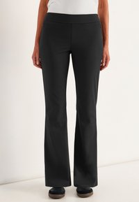 Zwarte rechte broek van een gladde, rekbare stof. Heeft een hoge tailleband en zijzakken. Strak om de heupen, breder aan de onderkant.