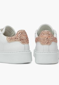 Sneaker bianche in pelle con un accento testurizzato in oro rosa sul tallone, caratterizzate da dettagli rialzati simili a cristalli e una robusta suola bianca.